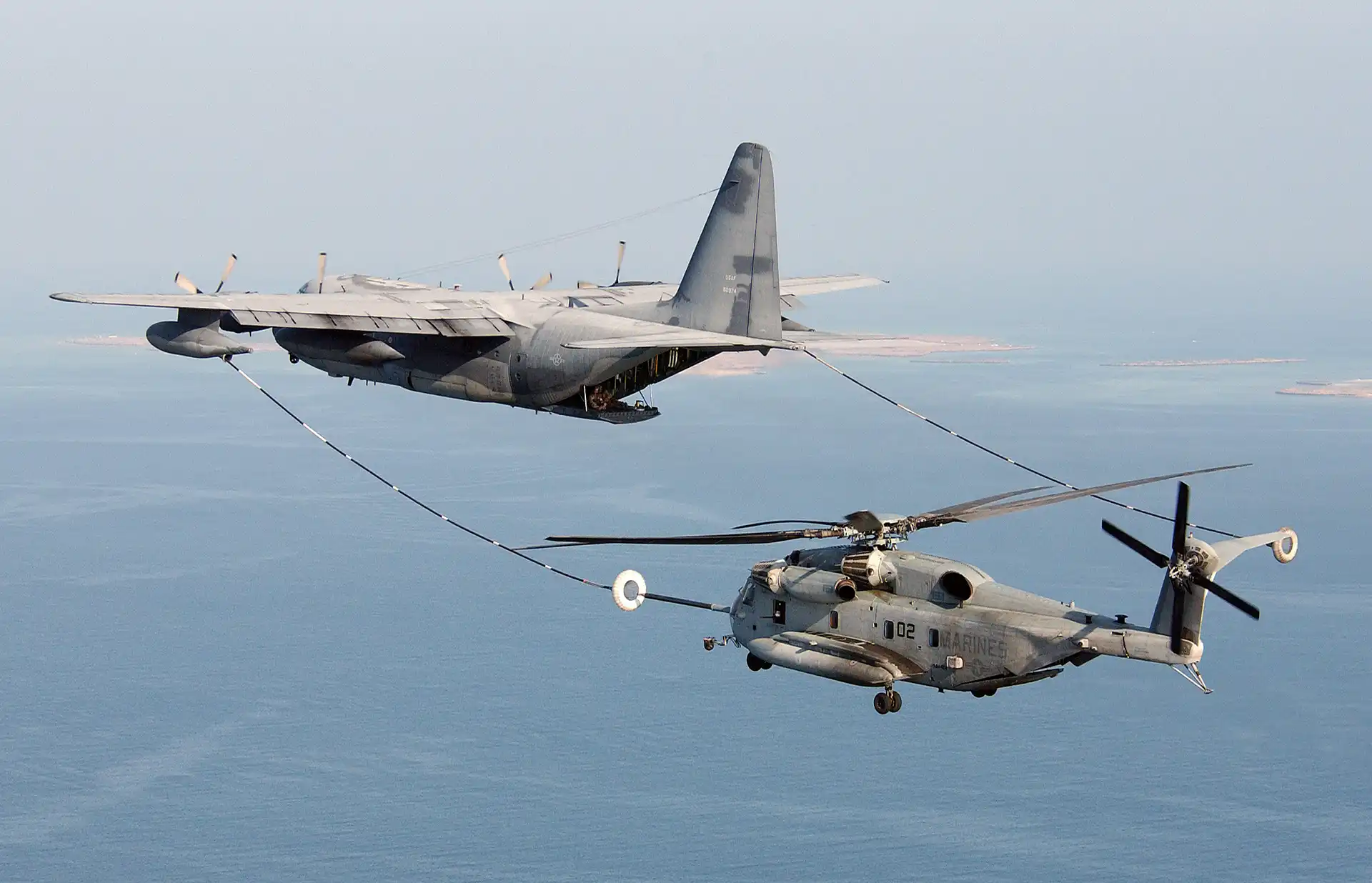 HC-130 tanker refueling an HH-60 helicopter over the ocean